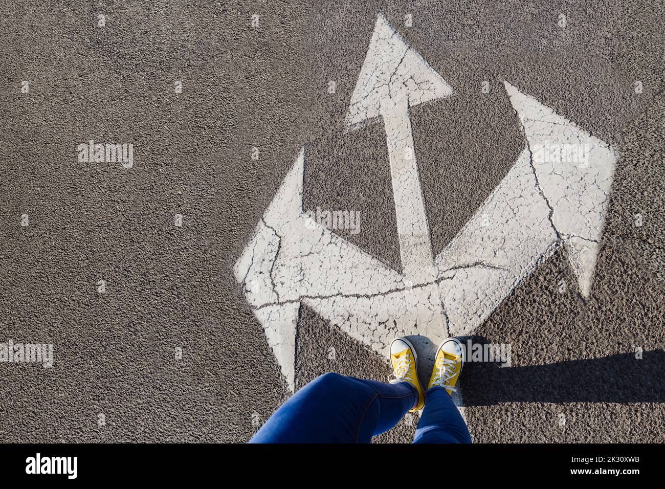 Woman standing on three way direction arrow sign on road Stock Photo