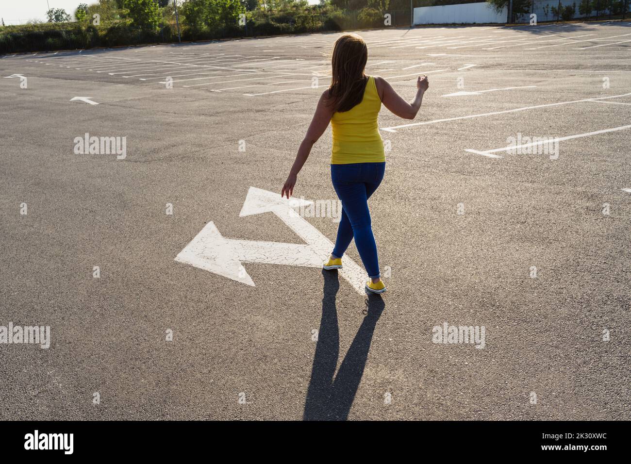 Woman walking on asphalt with arrow symbol Stock Photo Alamy