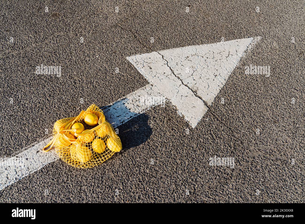 Mesh bag with lemons on arrow symbol Stock Photo