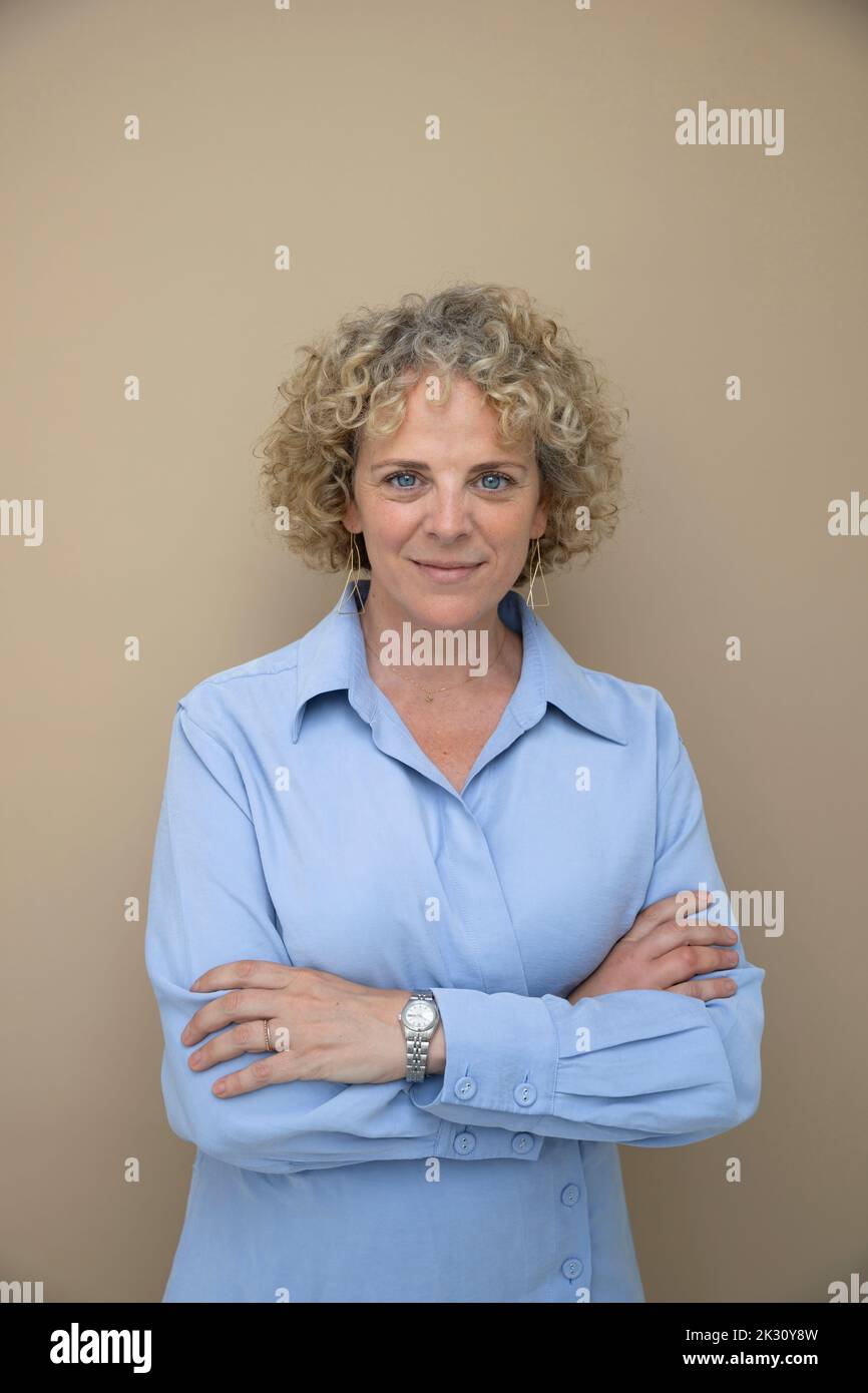 Businesswoman with arms crossed against brown background Stock Photo