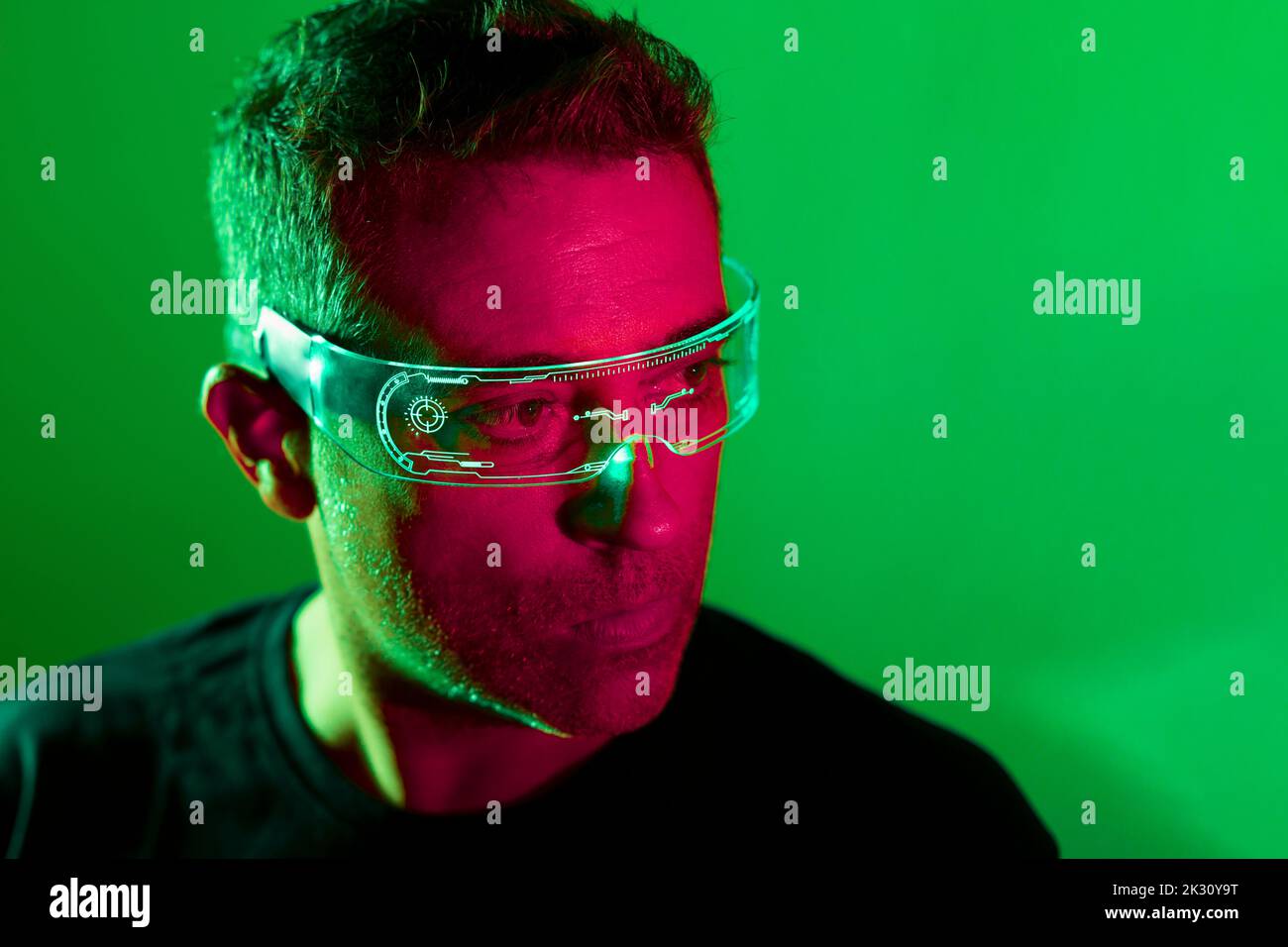 Contemplative man wearing smart glasses against green background Stock Photo