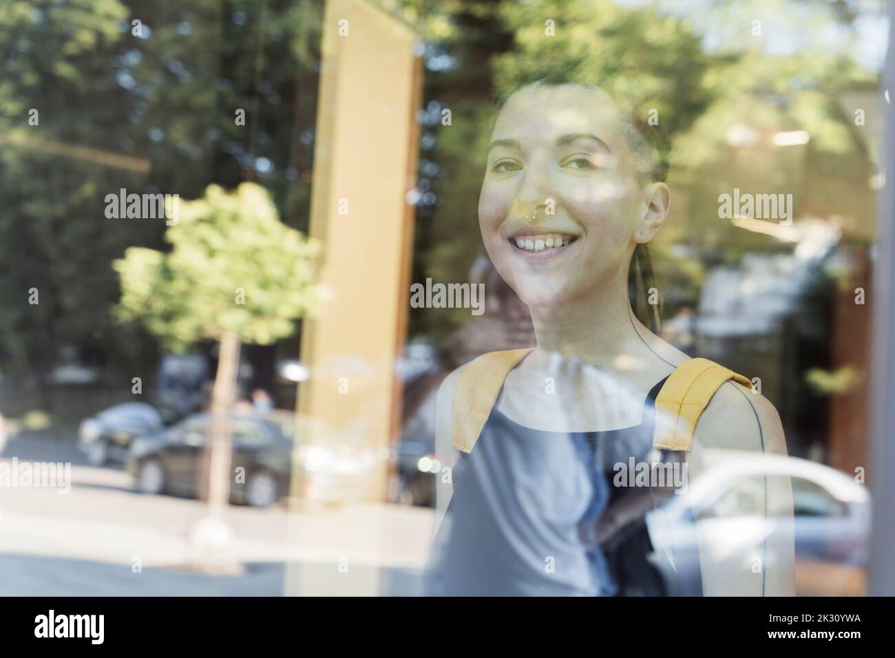 Smiling non-binary person seen through glass Stock Photo