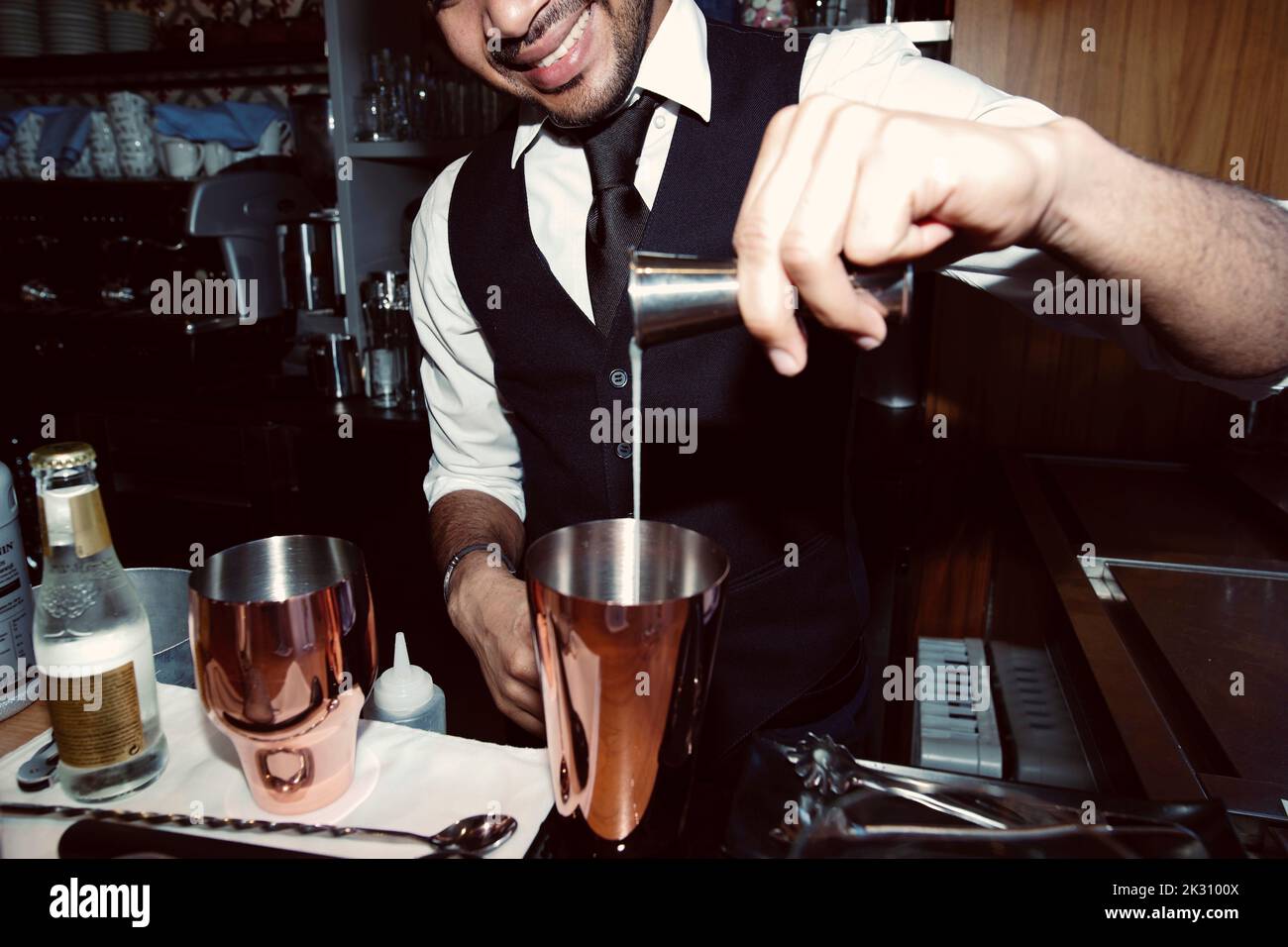 Barman pouring syrup into shaker through jigger at bar Stock Photo