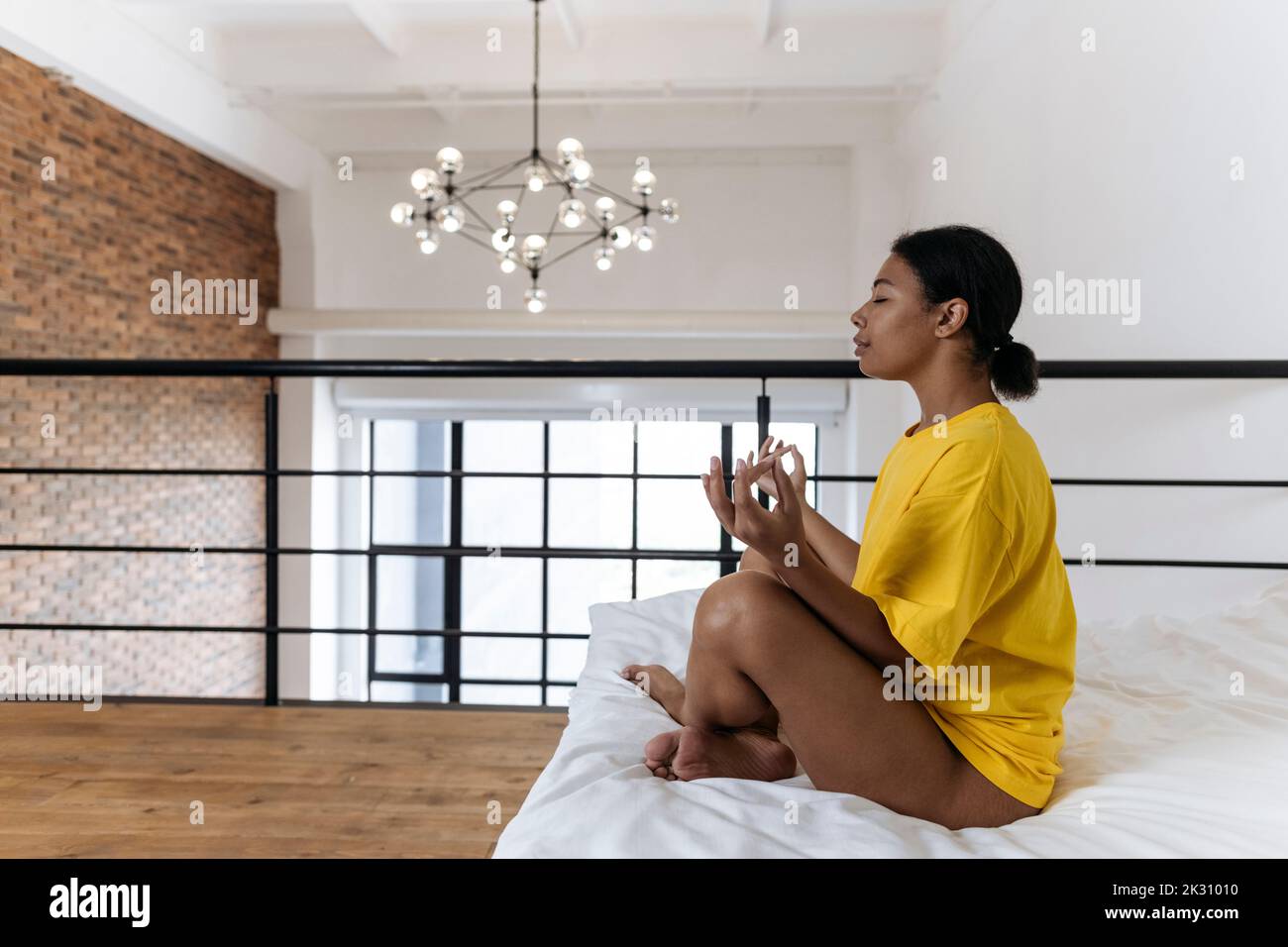 Young woman meditating in the morning sitting cross-legged on bed Stock ...