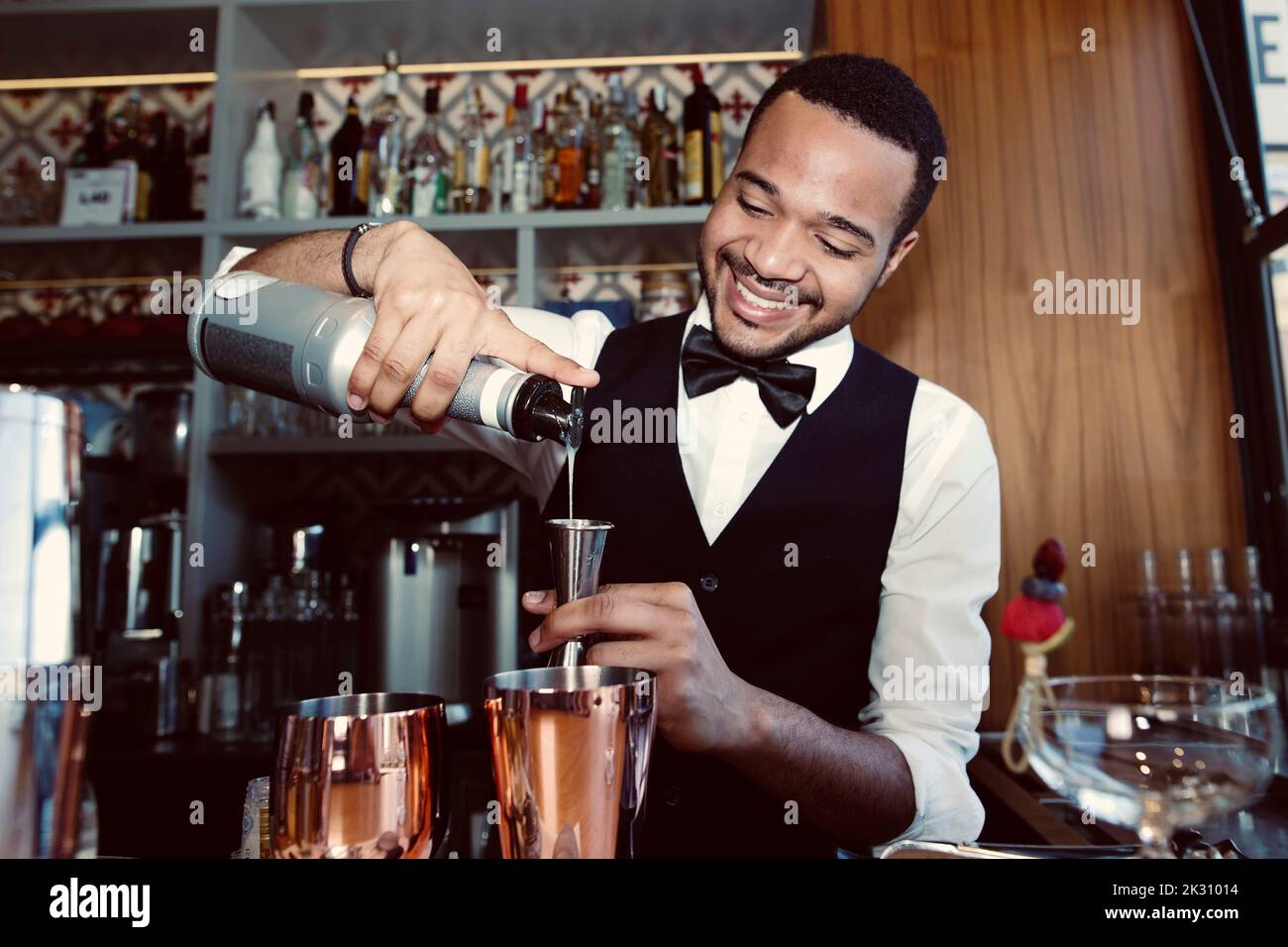 Smiling barman pouring syrup into jigger through bottle at bar Stock Photo