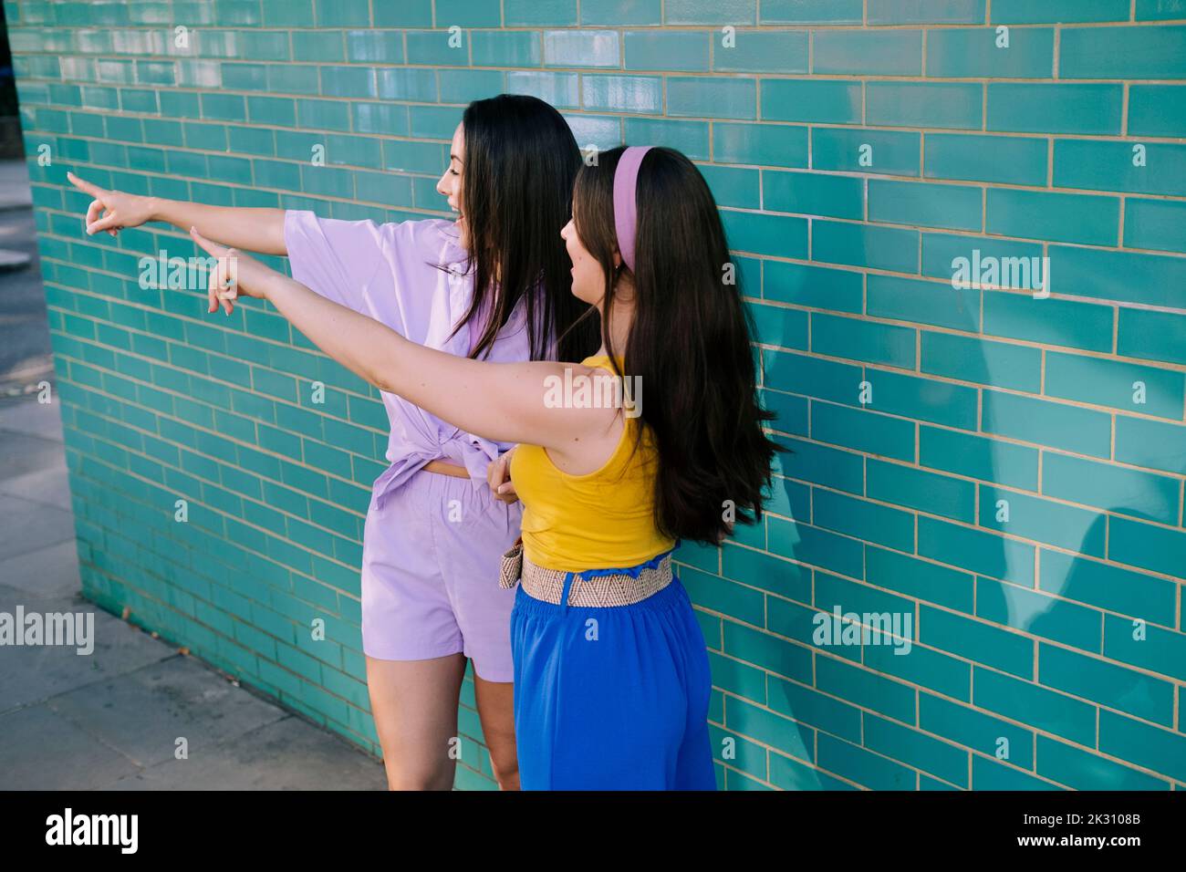 Pointing Near Young women pointing together near brick wall Stock Photo - Alamy
