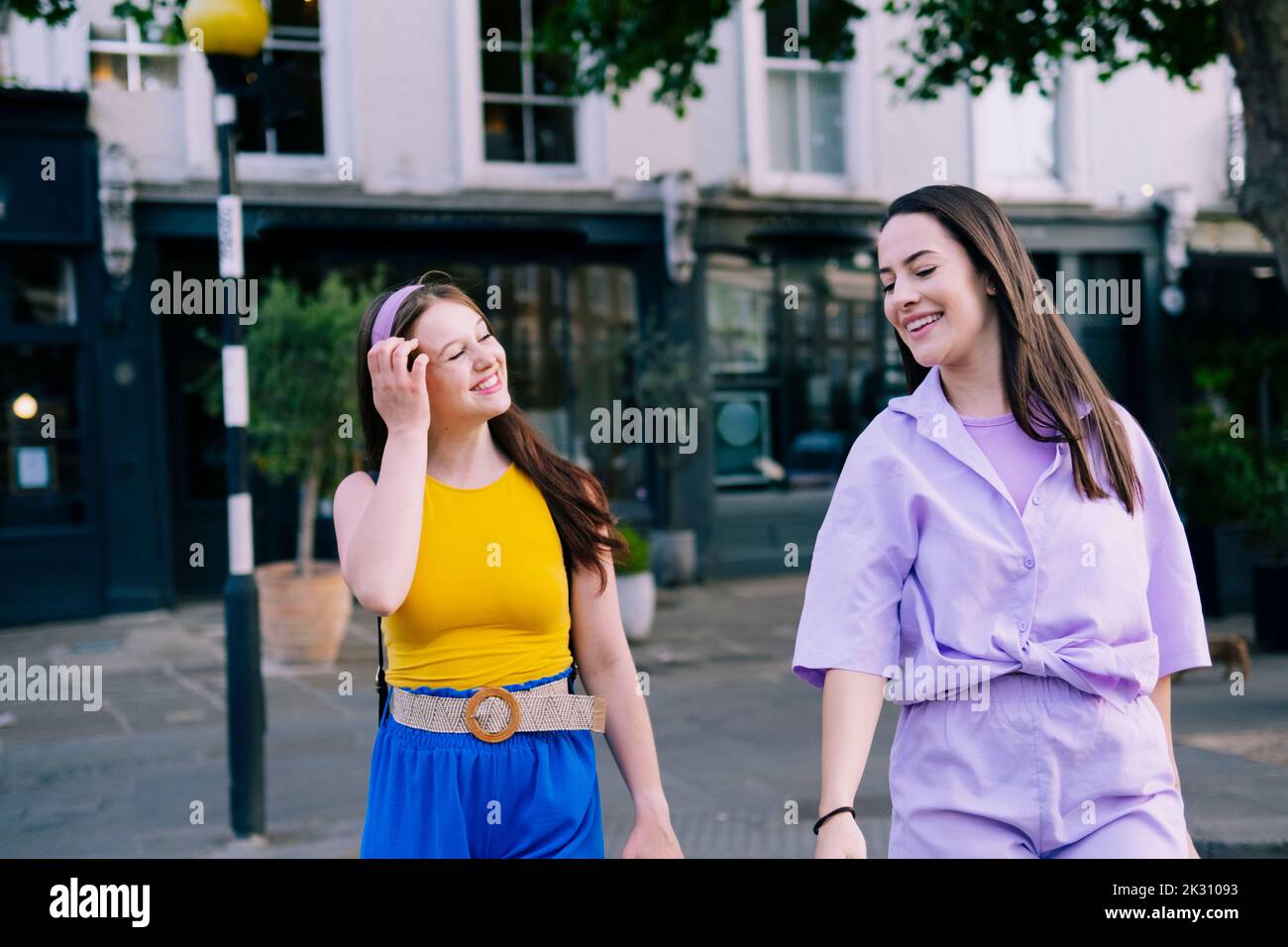 Two happy young women walking hand hand city hi-res stock photography ...