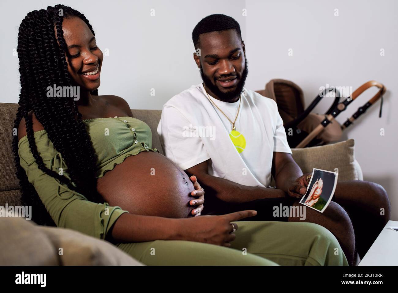 Man showing ultrasound picture of baby to pregnant woman at home Stock
