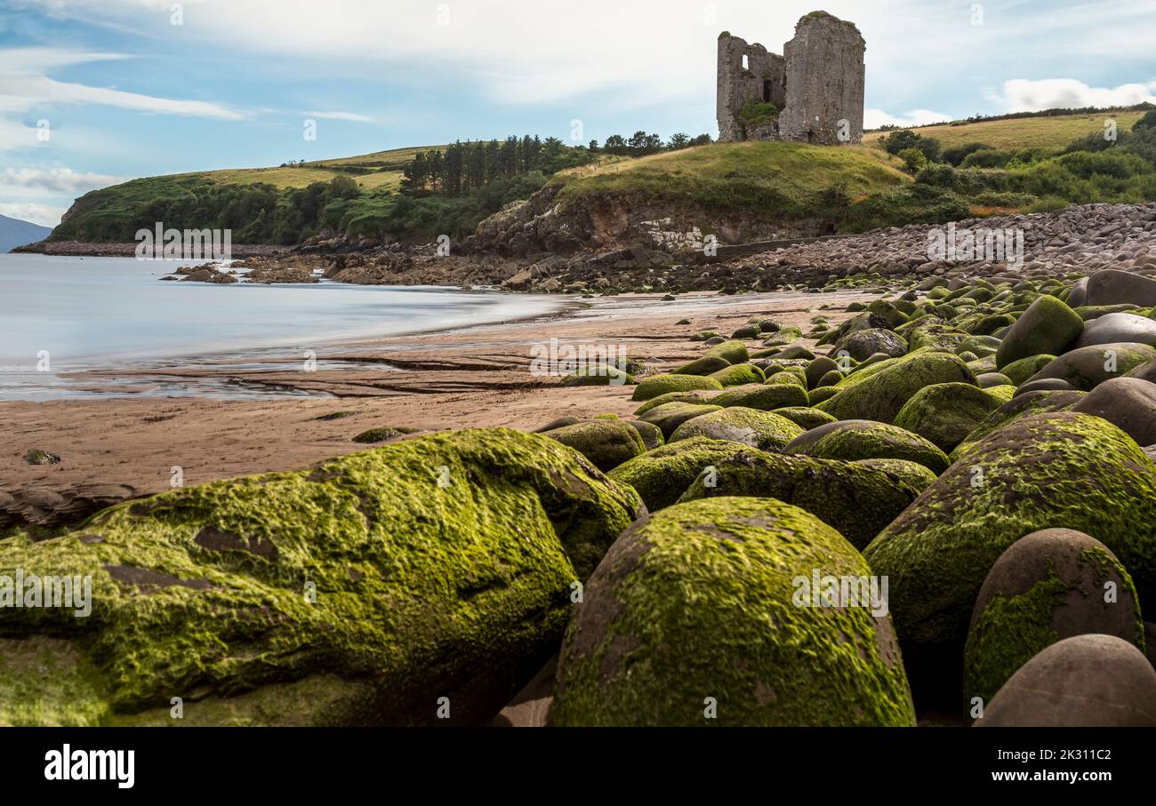Ireland, Kilmurry, Boulders lying along beach with old ruin in ...