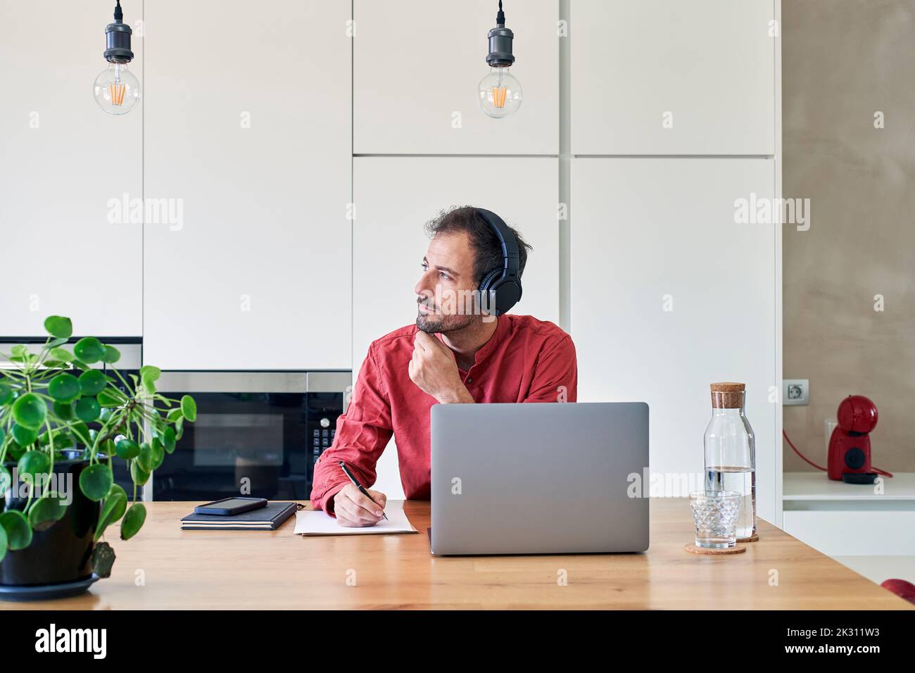 Thoughtful freelancer sitting with laptop at home Stock Photo
