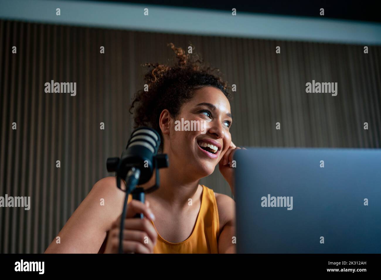 Happy radio presenter with microphone podcasting at workplace Stock