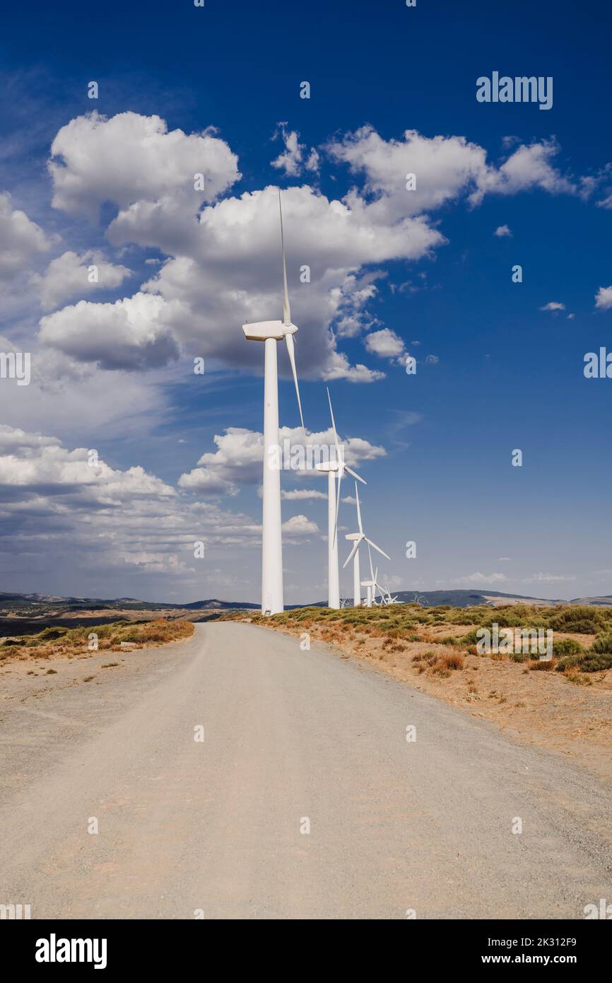 Wind turbines by cloudy sky at wind farm Stock Photo