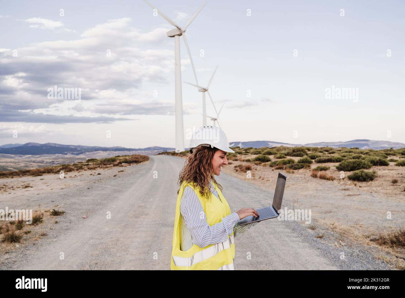 Smiling engineer working on laptop at wind farm Stock Photo