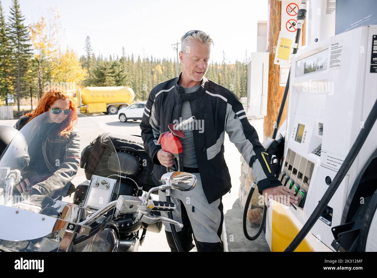 Motorcyclists refuelling at gas station Stock Photo