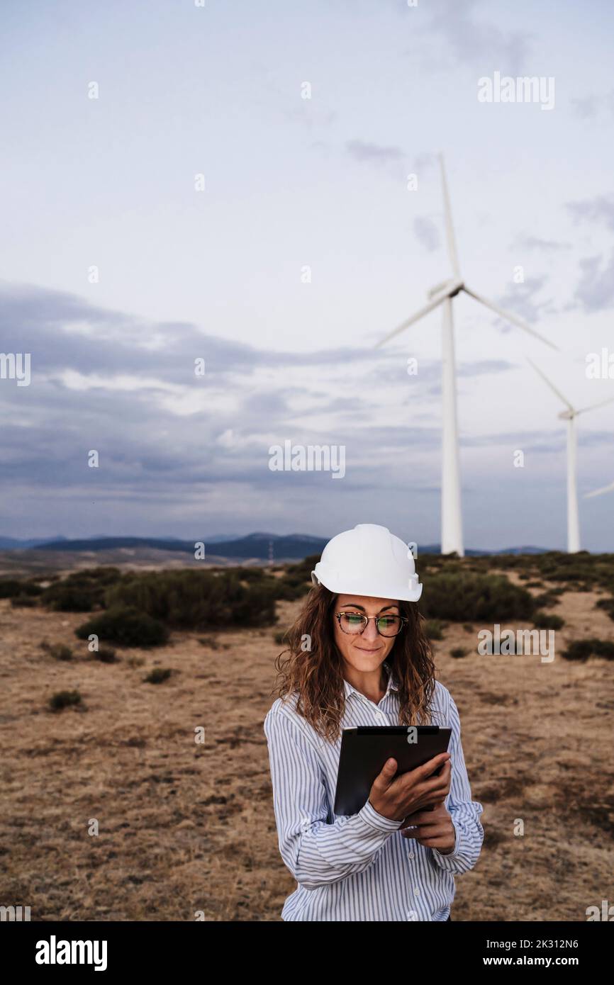 Engineer wearing hardhat using tablet PC at wind farm Stock Photo
