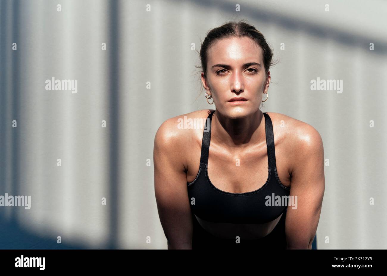Tired woman in front of wall on sunny day Stock Photo