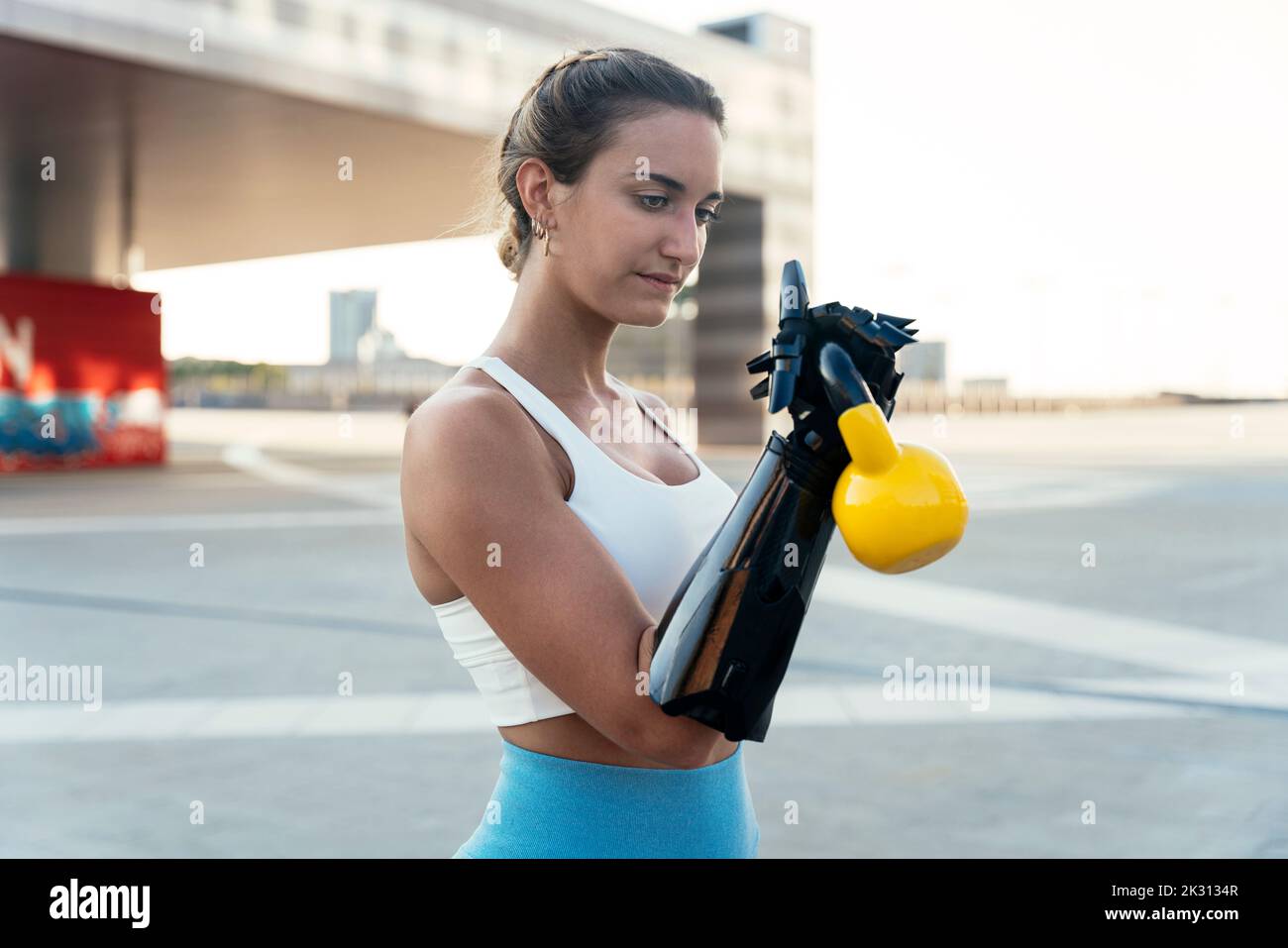 Young woman with arm prosthesis exercising with kettlebell Stock Photo
