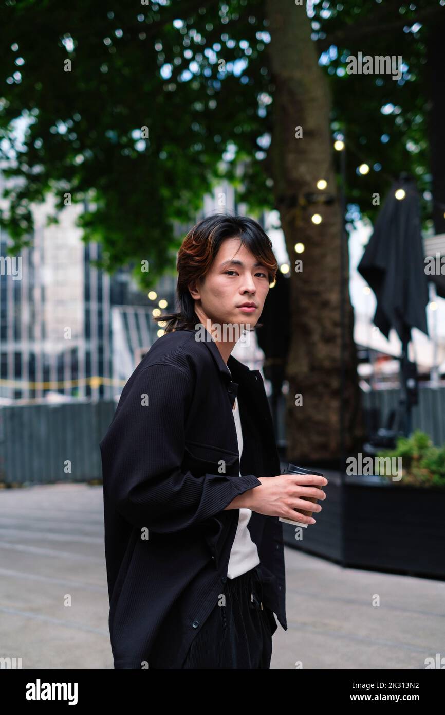 Young man with coffee cup standing on footpath Stock Photo
