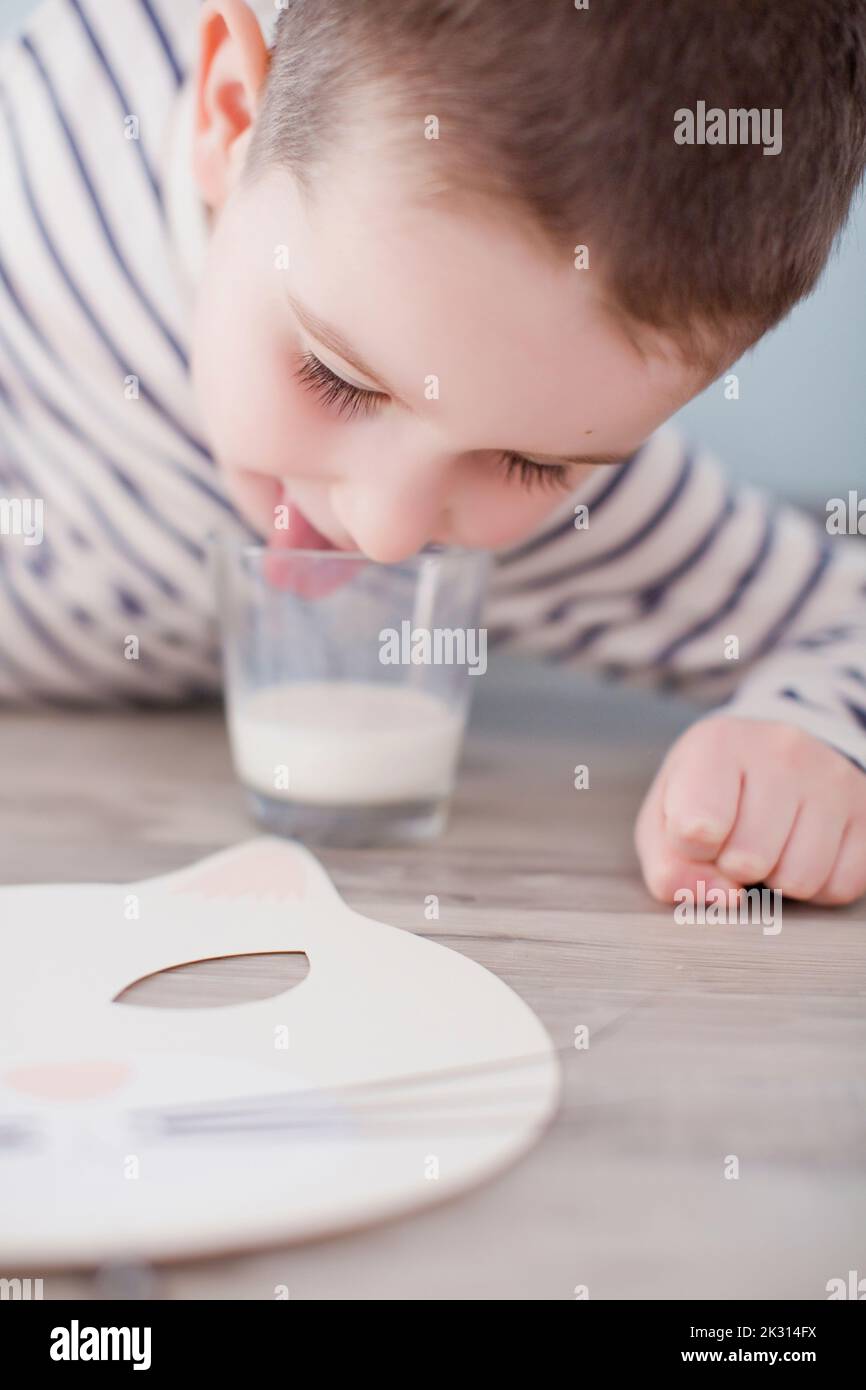 Boy licking glass of milk with Halloween mask Stock Photo