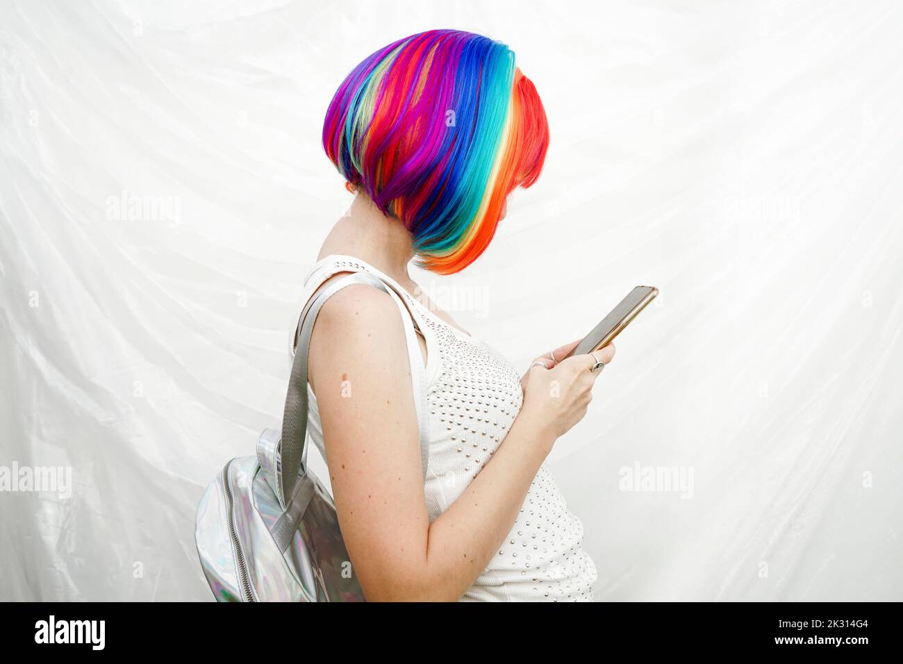 Woman with multi colored hair using smart phone by plastic backdrop Stock Photo