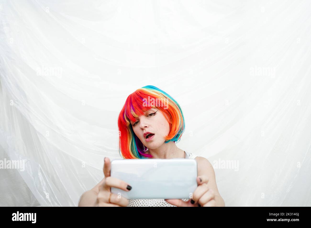 Woman with multi colored hair taking selfie through smart phone Stock Photo