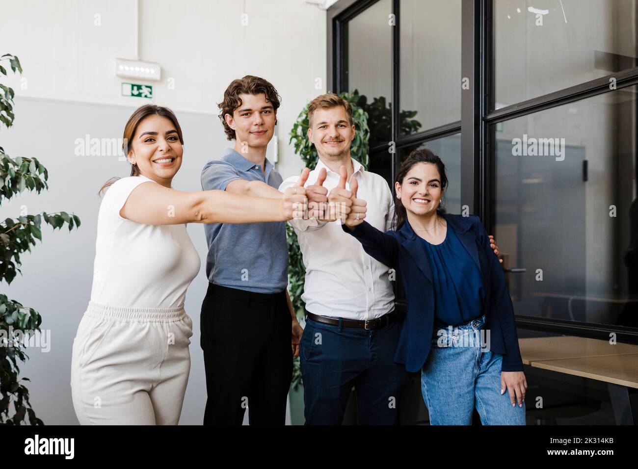 Business people standing together showing thumbs up in office Stock ...