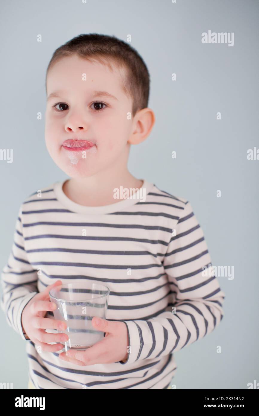 Boy with striped shirt licking lips in front of wall Stock Photo