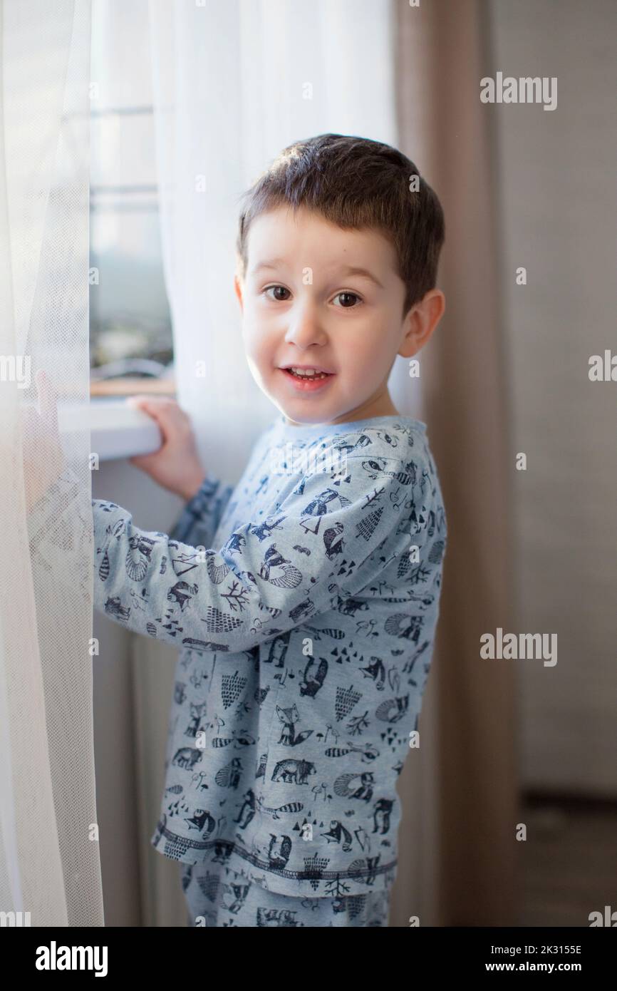 Cute boy standing by window at home Stock Photo Alamy