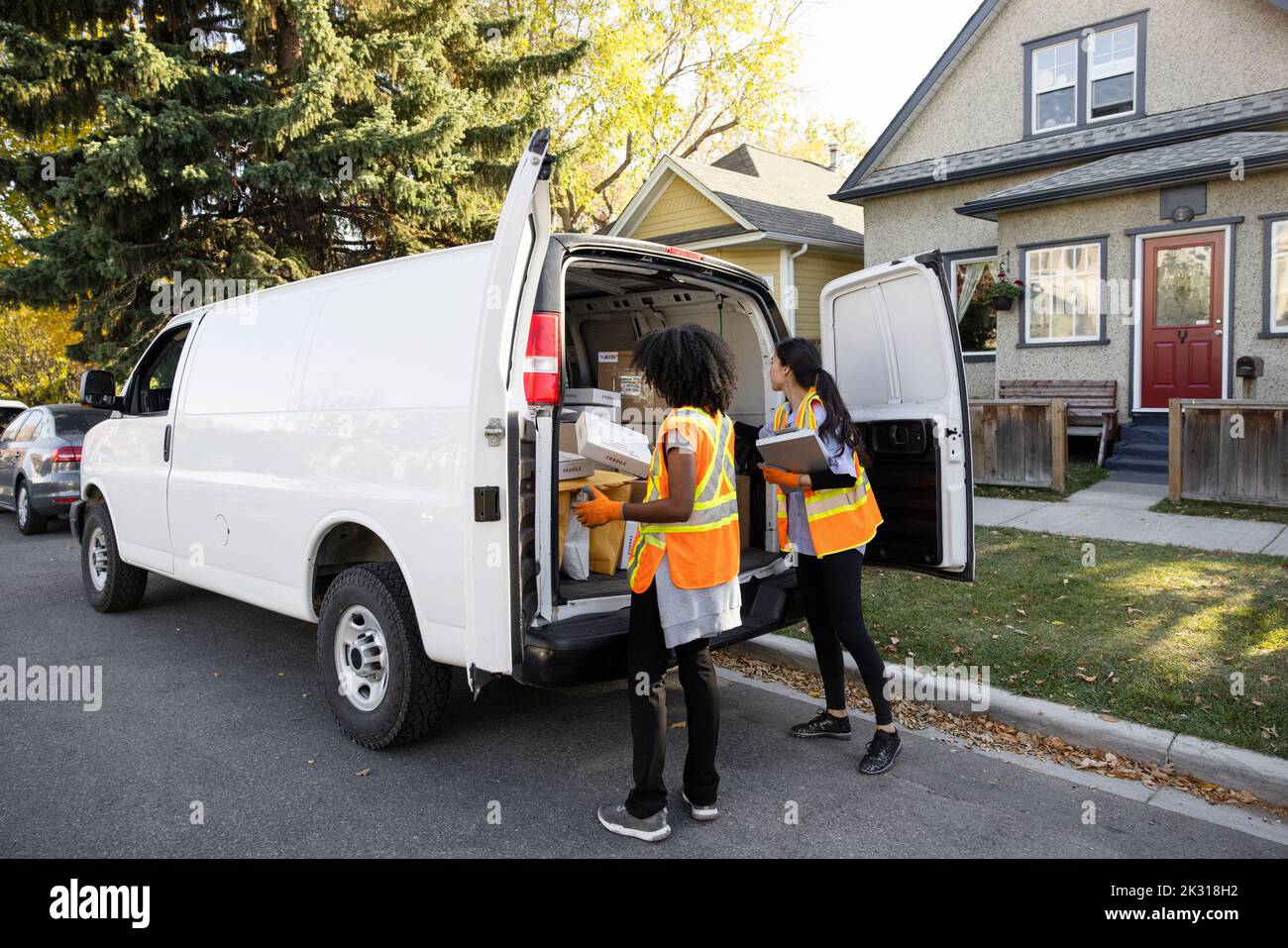 Coworkers checking parcels at rear of van Stock Photo - Alamy