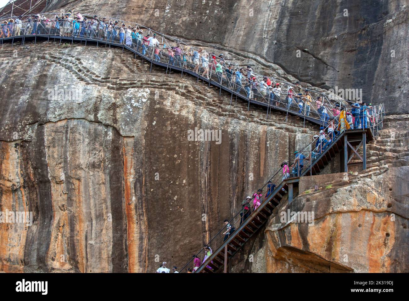 Visitors to Sigiriya Rock Fortress in Sri Lanka descend down the stairway from the summit to the Lion Platform. Stock Photo