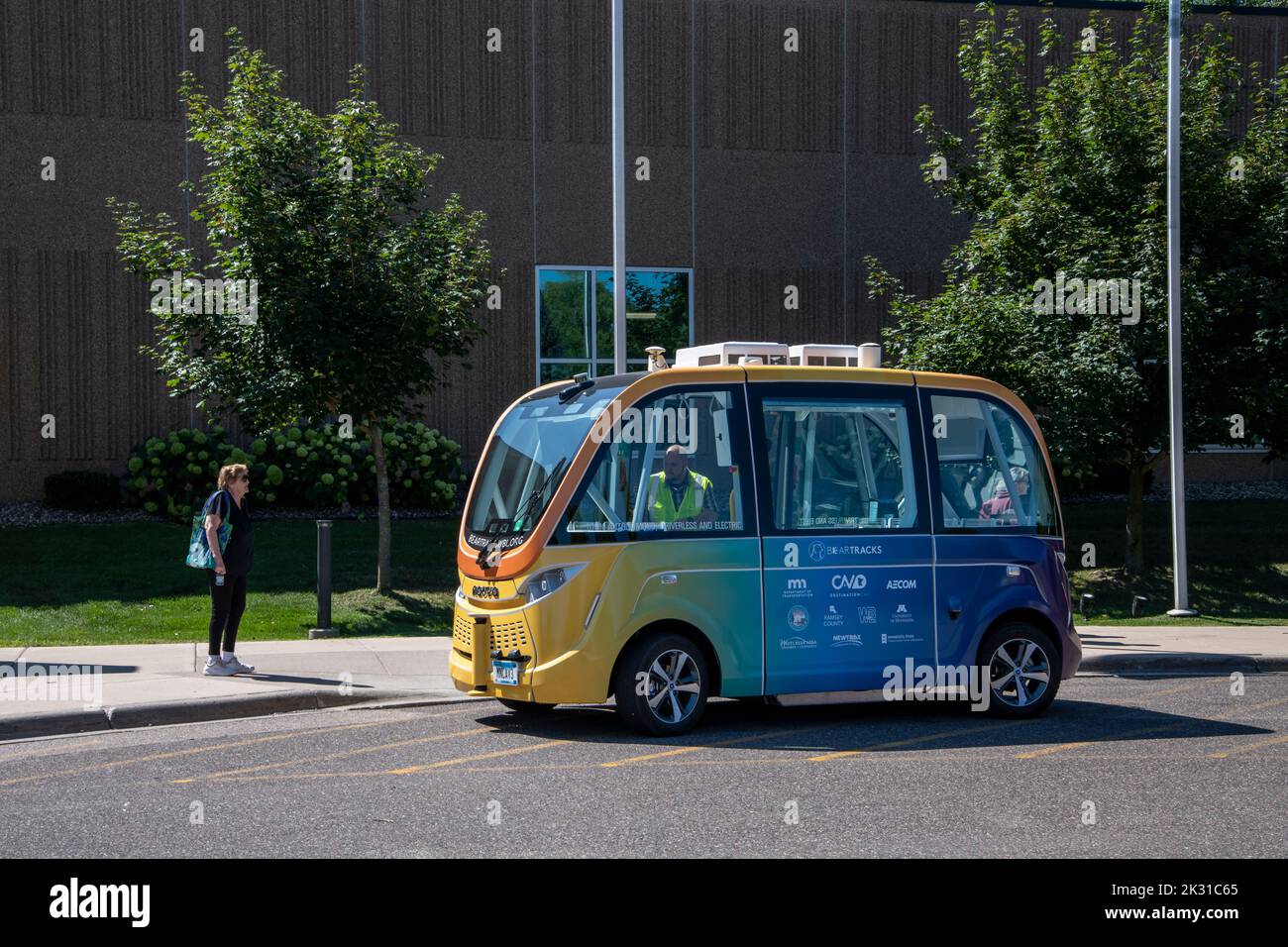 White Bear Lake, Minnesota. August 9 2022. A woman waits to ride on the self-driving low speed multi-passenger electric shuttle. Bear Tracks.is a rese Stock Photo