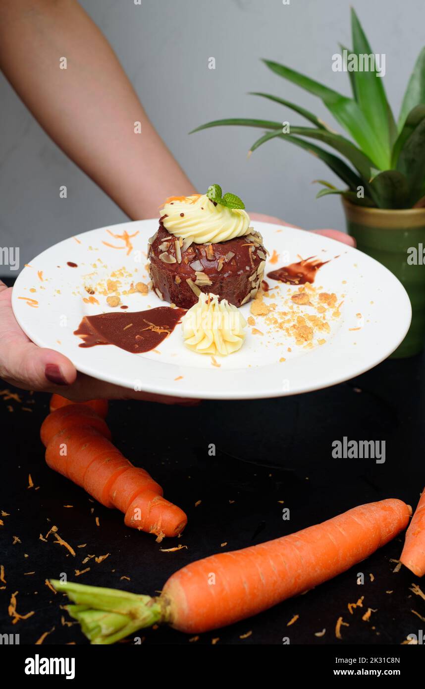 Hands holding a plate with Carrot chocolate cake Stock Photo