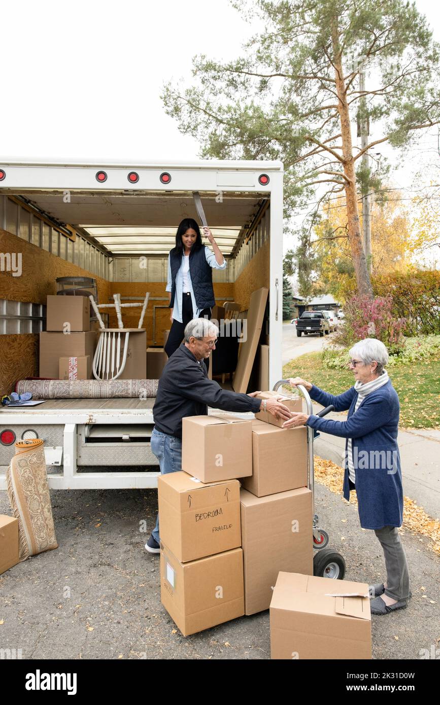 Daughter helping senior parents unload moving van Stock Photo