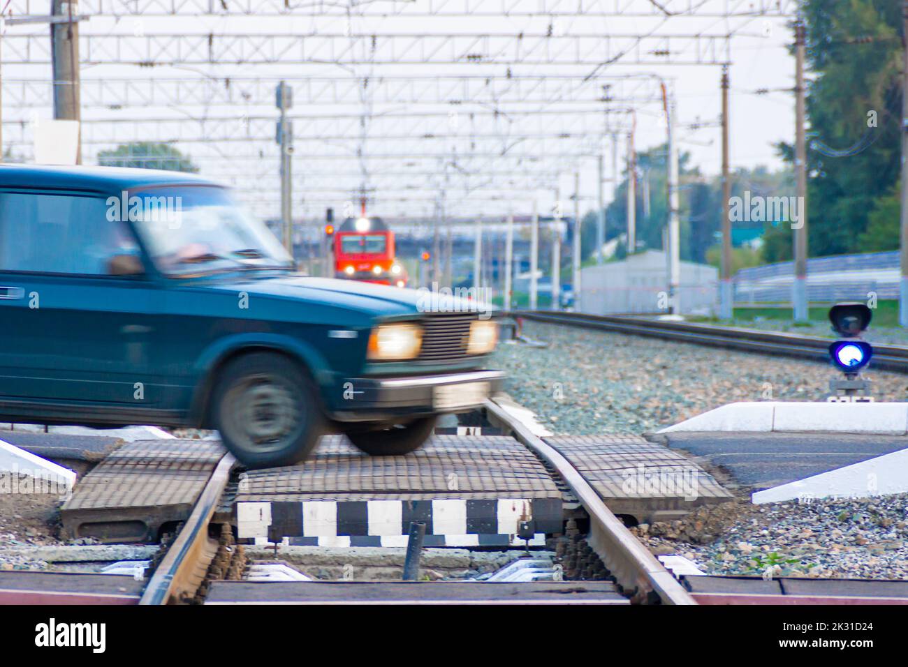railway crossing through which an old passenger car passes while crossing the railway tracks in front of an approaching train, selective focus Stock Photo
