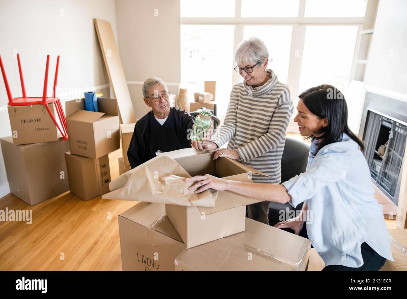 Daughter helping senior parents unpack in new home Stock Photo