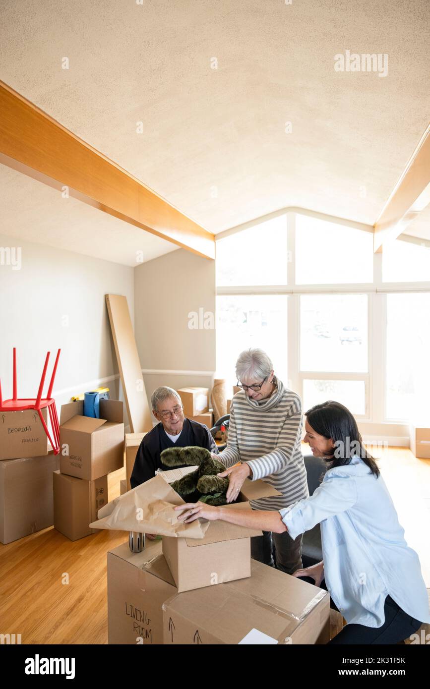 Daughter helping senior parents unpack in new home Stock Photo