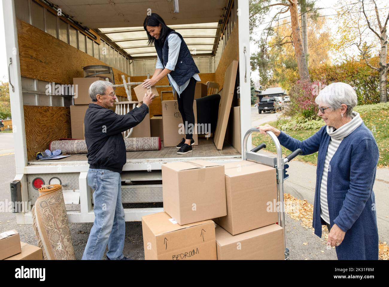 Daughter helping senior parents unload moving van Stock Photo
