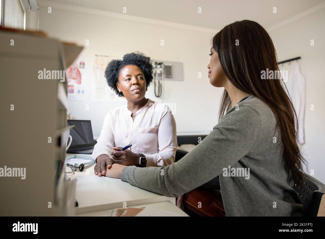 Female doctor comforting patient in clinic doctor's office Stock Photo