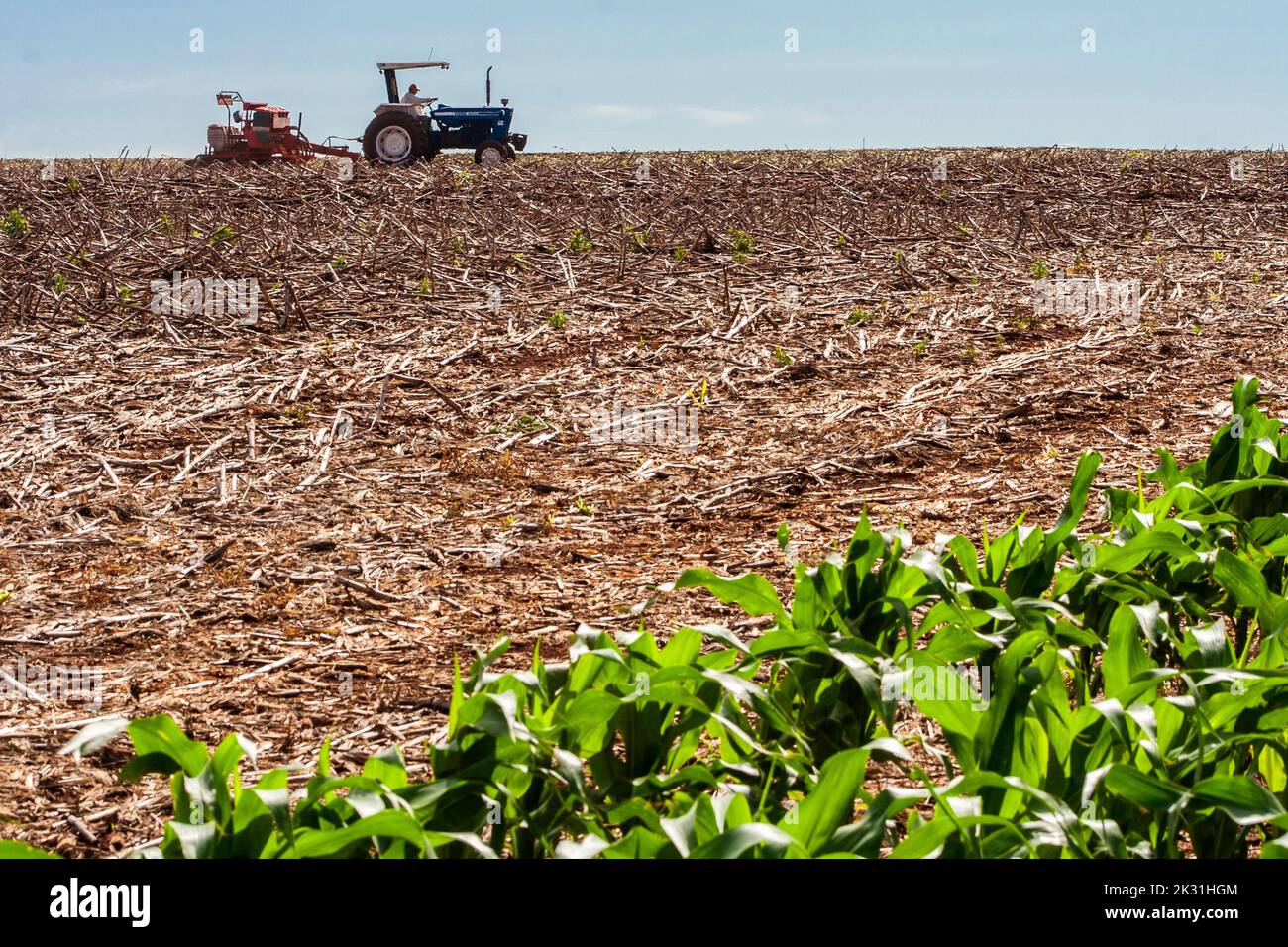 Parana, Brazil, October 28, 2009. Farmer in tractor sowing crops at field with seed scattering agricultural machine Stock Photo
