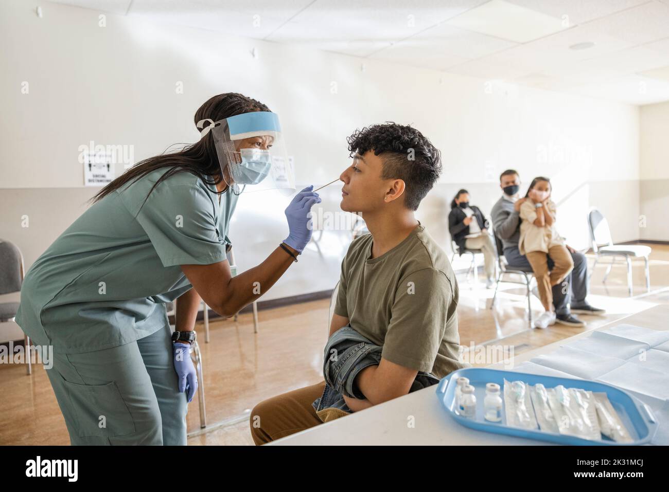 Nurse in PPE taking COVID-19 nasal swab for patient in clinic Stock Photo