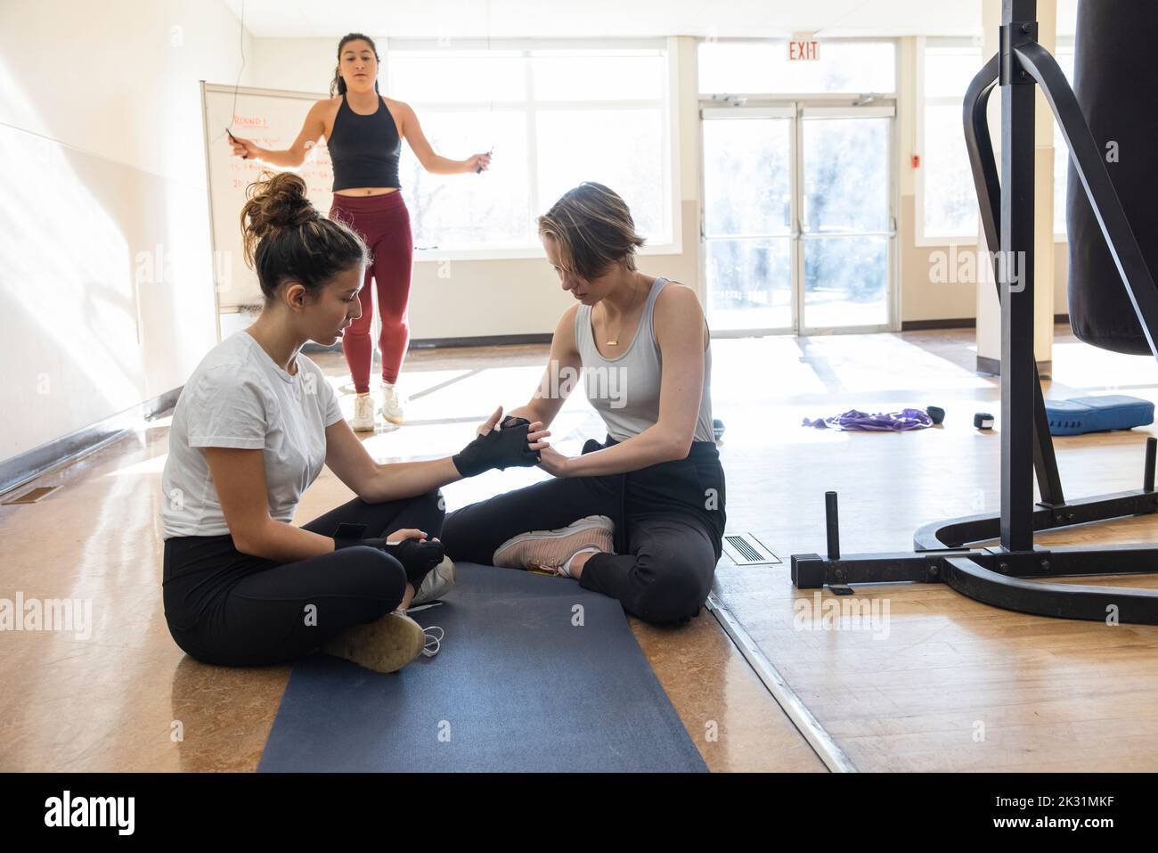 Teen girls putting on wrist wrap for boxing in gym studio Stock Photo