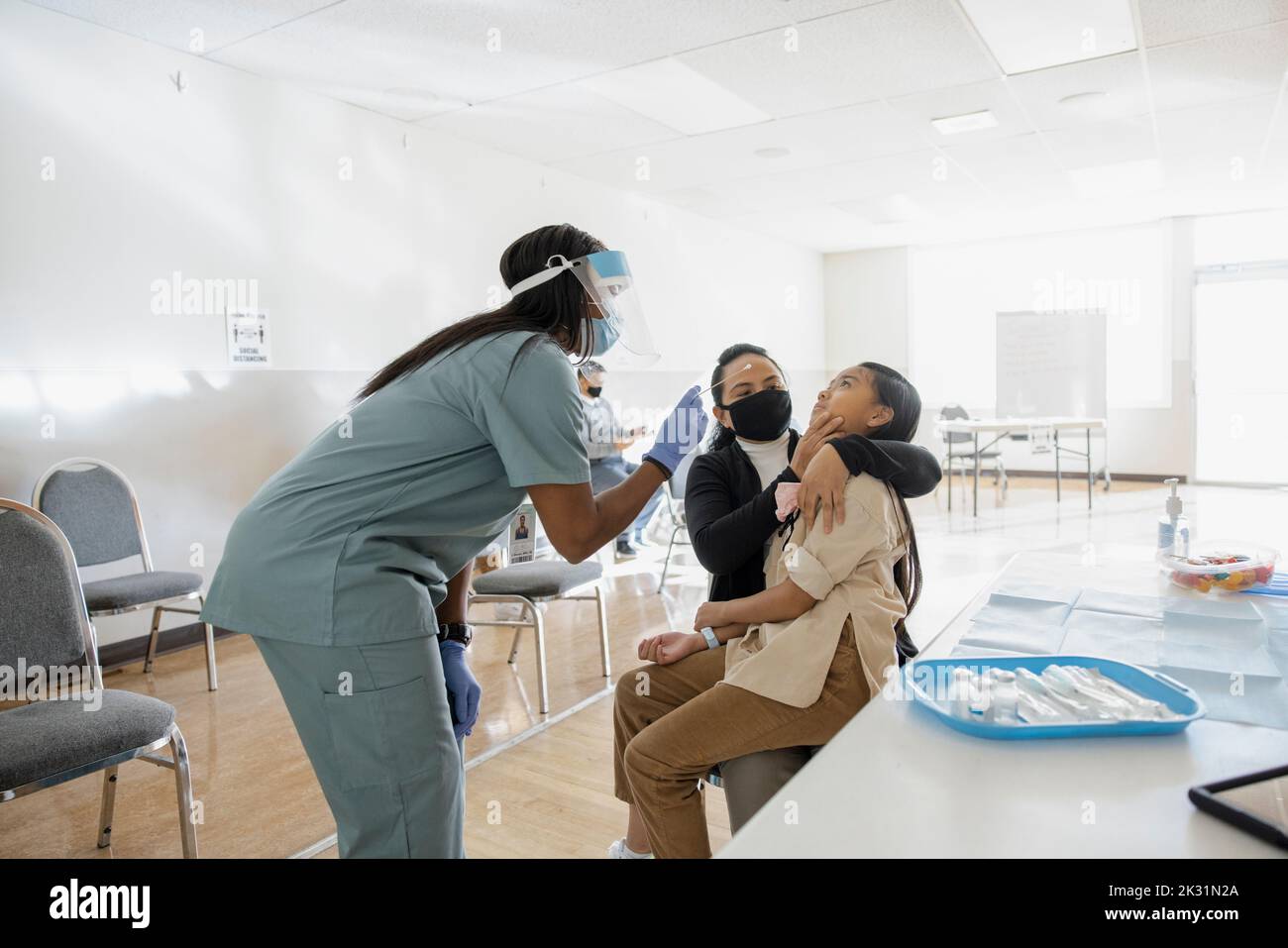Nurse taking COVID-19 nasal swab test for girl patient in clinic Stock Photo