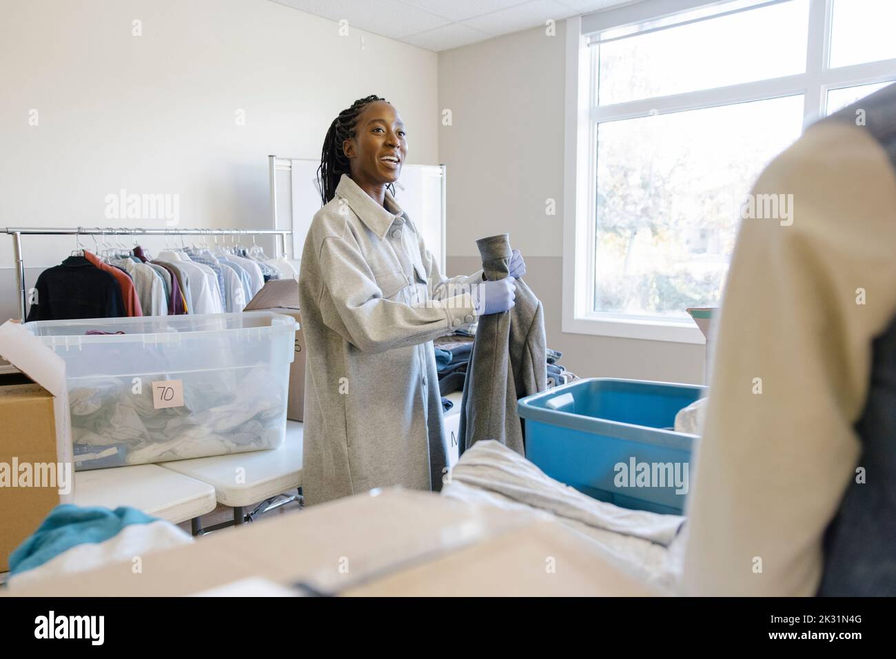 Young female volunteer sorting clothing donations in community center
