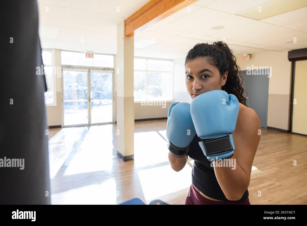 Portrait confident determined teen girl in boxing gloves at gym Stock
