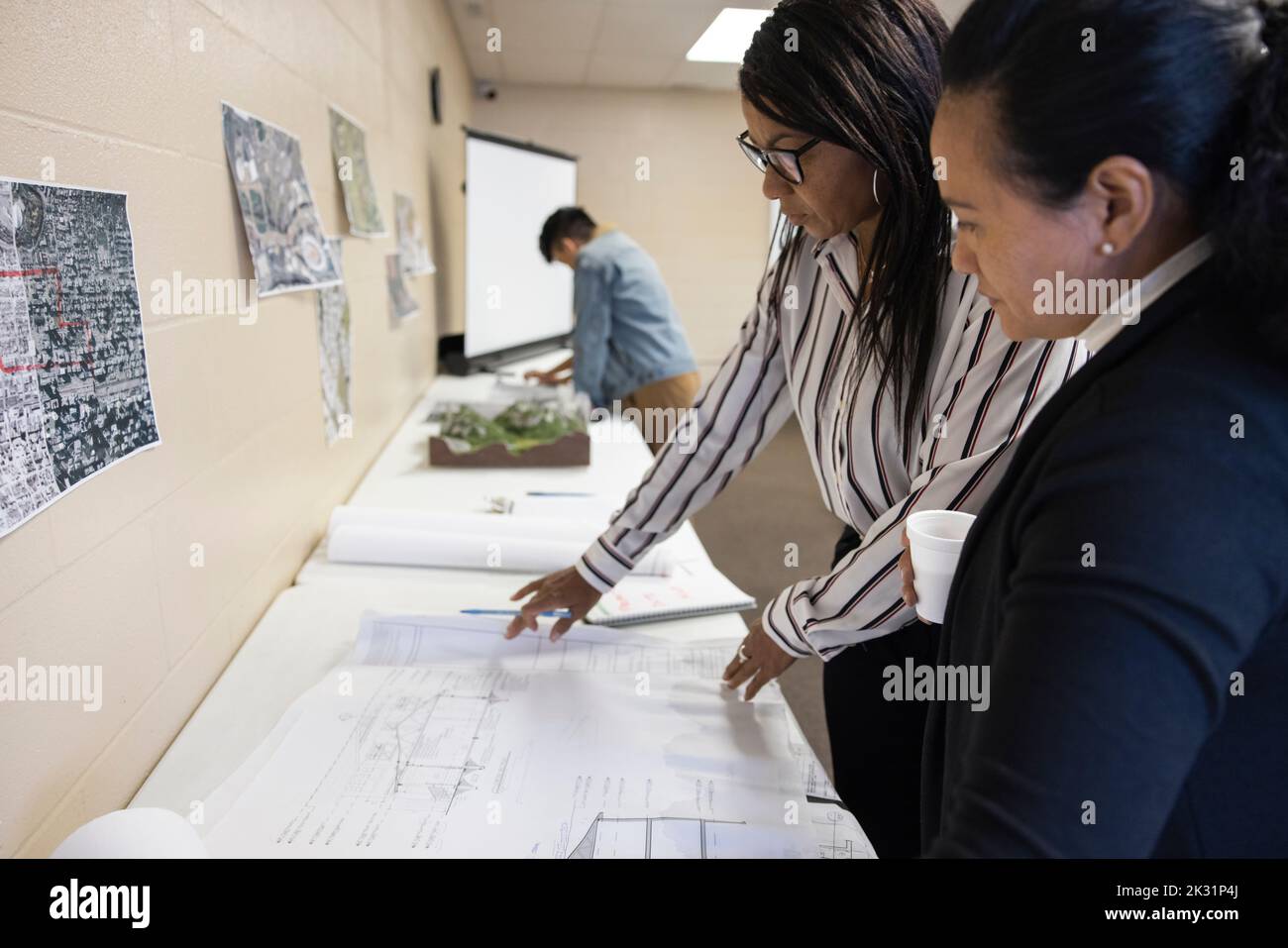 Women discussing blueprints in urban planning meeting Stock Photo