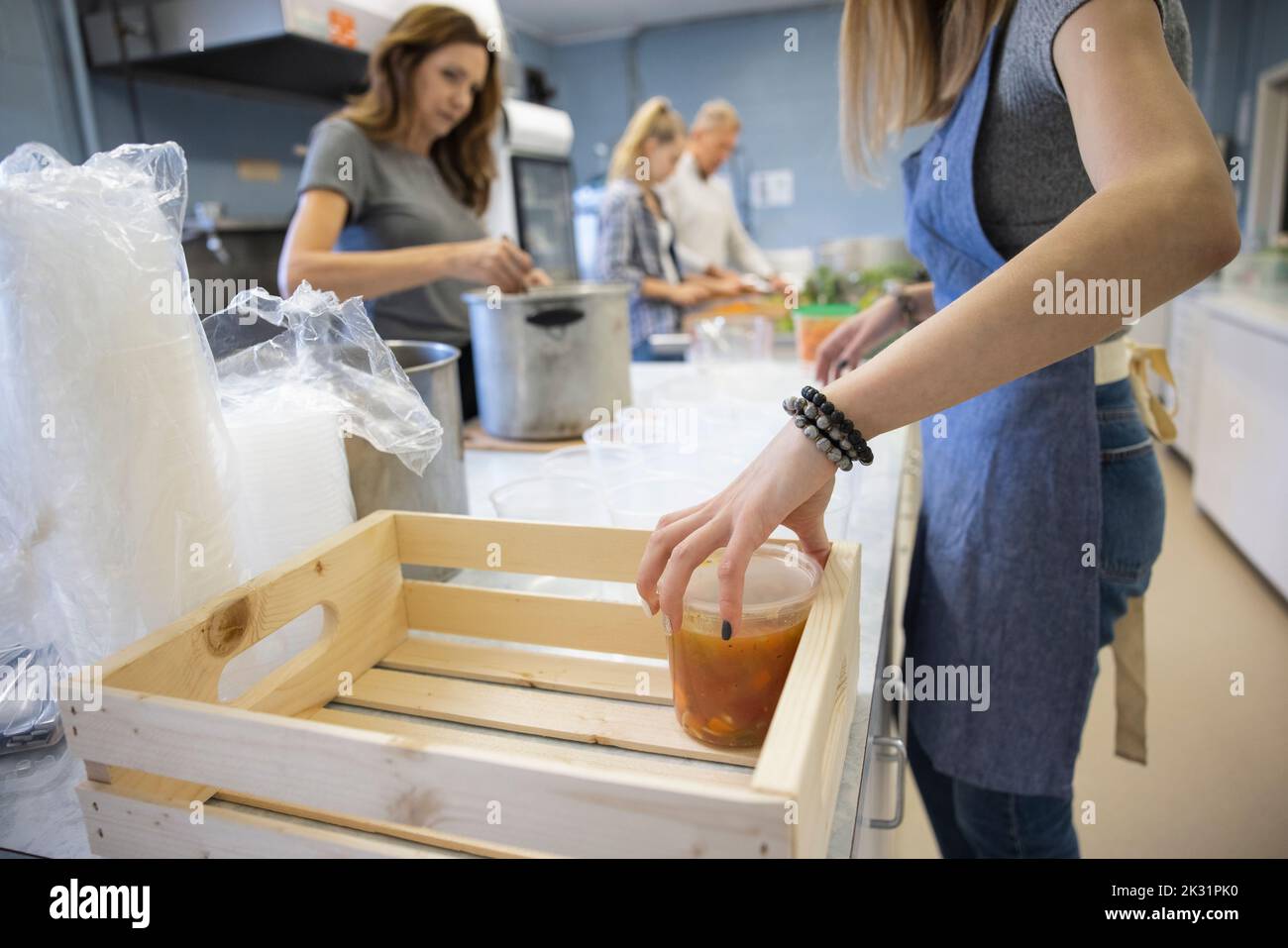 Family volunteers preparing soup in community center soup kitchen Stock