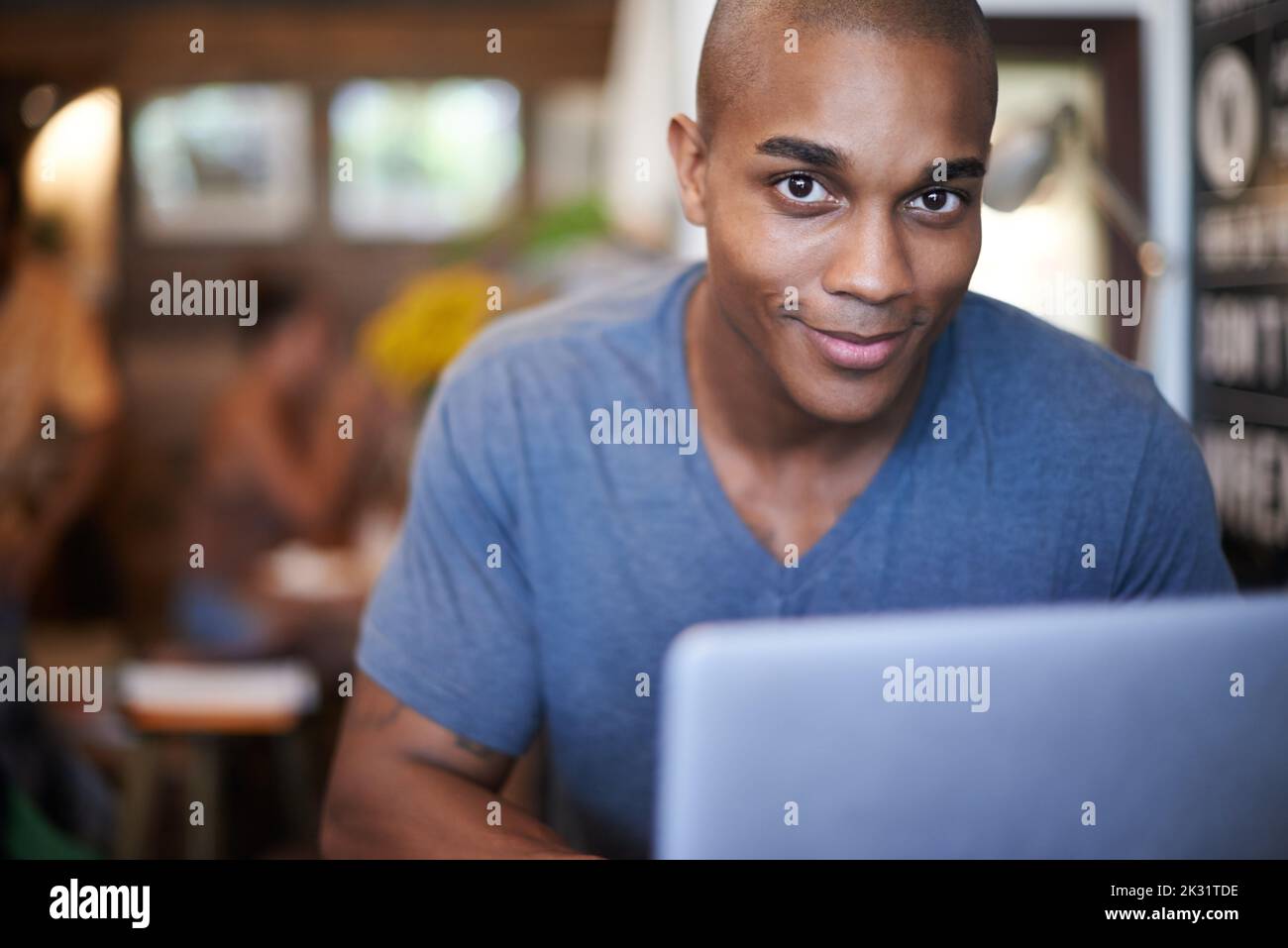 I get some of best work done here. a handsome young man using his laptop in a coffee shop. Stock Photo