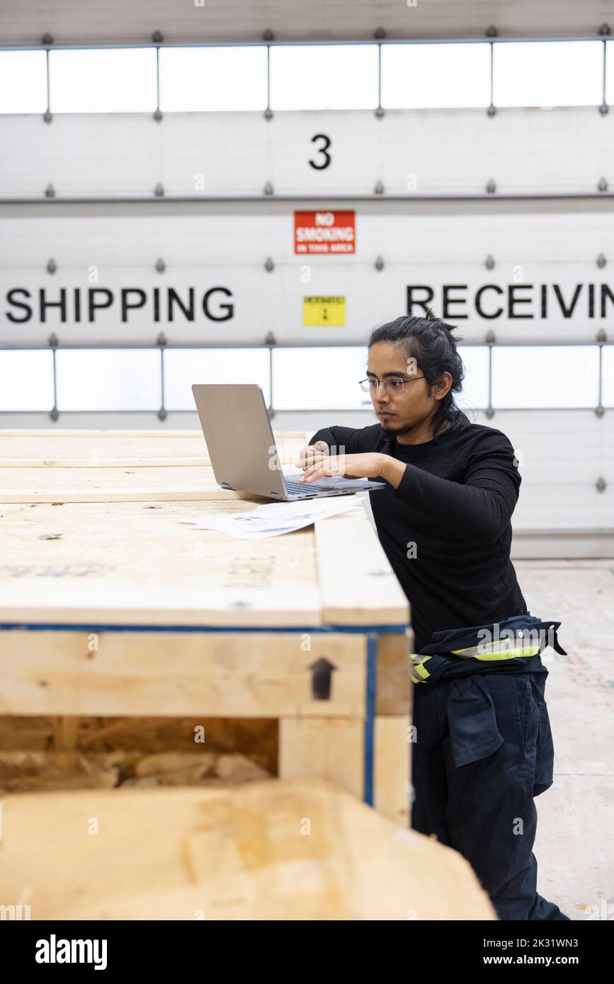 Technician working on laptop in loading bay Stock Photo