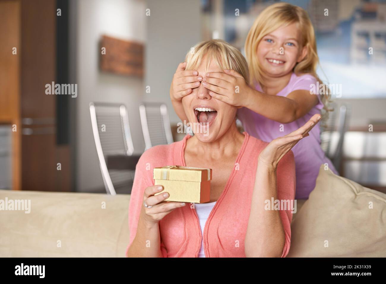 Open your hands and close your eyes for a big surprise. a young girl surprising her mother with a gift. Stock Photo