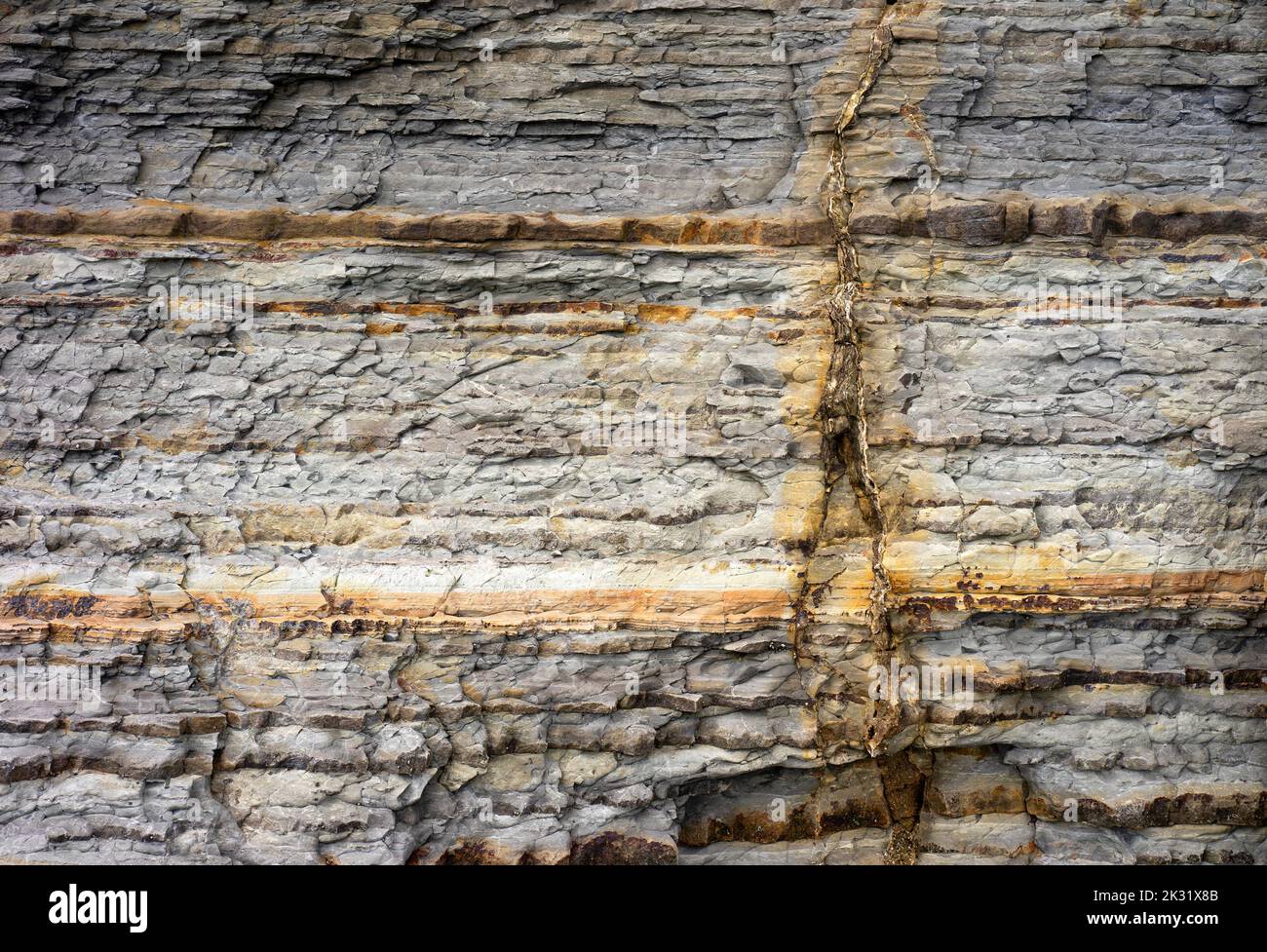 Vertical vein of a mineral deposit exposed in rocks. Stock Photo